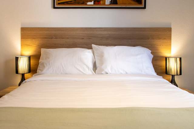 Dormitorio principal con cabecera de madera y lámparas