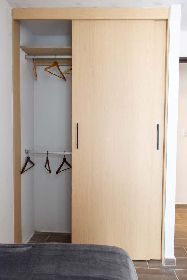 Clóset con puerta corrediza abierta y tubo para colgar